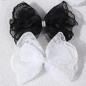 Detail of lace bow hair clips featuring delicate pearls and elegant layered tulle fabric