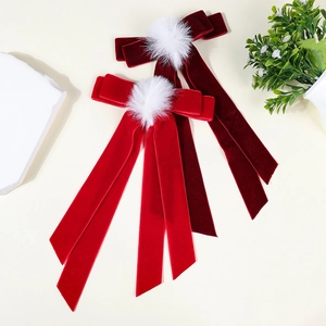 Close-up of velvet bow hair clips with white pom-poms in bright red and wine red colors