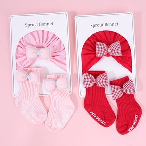 Detalle de set de gorros turbante y calcetines acanalados rosas y rojos con lazos suaves