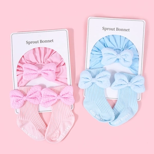 Detail view of cotton baby bonnets and ribbed socks set with large decorative bows