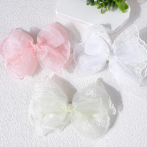 Detailed view of layered lace and organza hair clips with beads in pink, white, and beige