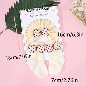 Detalle del conjunto de gorro y calcetines para bebé con lazos de lunares en cartón