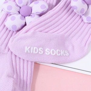 Gros plan de chaussettes bébé en maille lavande avec fleur 3D et semelles antidérapantes