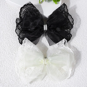 Close-up of black and white lace hair clips with elegant pearls and organza ribbons