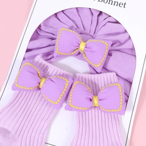 Detalle del conjunto morado para recién nacido con gorro de lazo y calcetines de punto