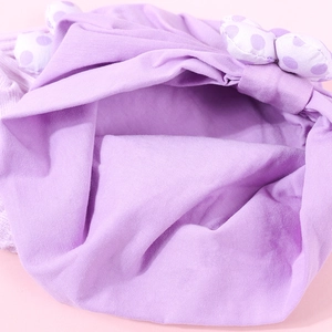 Détails rapprochés de la couture du bonnet bébé en coton avec nœud à pois violets
