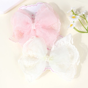 Detailed view of pink and white lace bow hair clips with pearls on display card