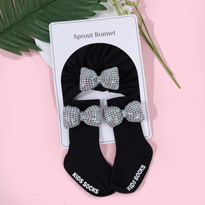 Dettaglio del set cappello e calzini in cotone per neonati con fiocchi di paillettes