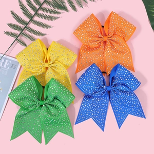 Detail of four colorful bow hair clips with ribbed texture and sparkling rhinestones