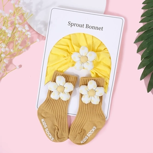 Ensemble turban jaune à volants et chaussettes à fleurs pour bébé sur fond décoratif