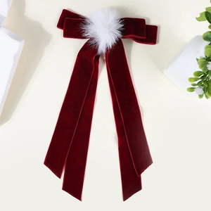 Detail of burgundy velvet hair clip with white fur ball and long elegant ribbons