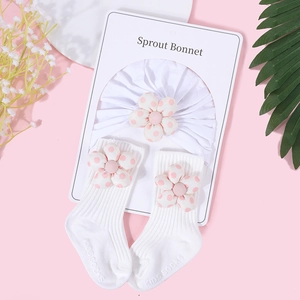 Détail d'un ensemble bonnet et chaussettes bébé blanc avec fleurs à pois roses