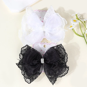 Detail of lace bow hair clips with faux pearls on display card with daisy decor
