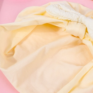 Detailed close-up of soft yellow cotton baby hat with white waffle textured bow