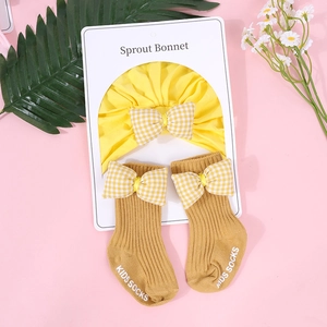 Detalle del conjunto de gorro de turbante amarillo y calcetines con lazos de cuadros