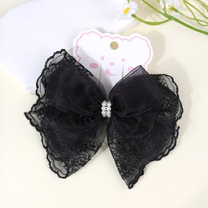 Detail of a black lace bow hair clip with white pearls on a bear display card