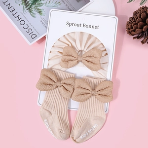 Detail of soft cotton baby headband and socks set with vintage coffee bows in cream white