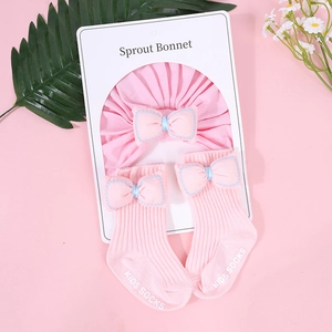 Detalle del conjunto de gorro rosa plisado y calcetines con lazo en tarjeta blanca