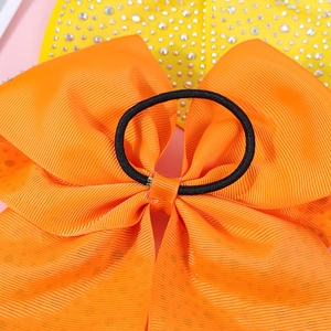 Macro shot of large orange ribbed bow hair tie with subtle sequins and black elastic band