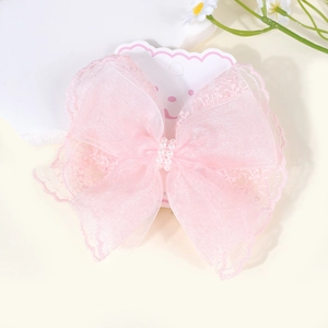 Close-up of pink lace bow hair clip with white pearls on a decorative display card
