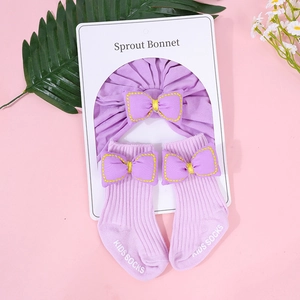 Detalle del conjunto de diadema y calcetines para bebé en lila con lazos y tejido de punto