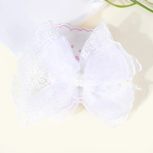 Detailed macro view of white lace bow hair clip with mesh layers and faux pearls