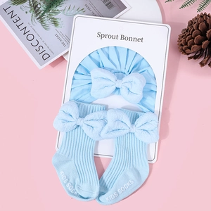 Detail view of light blue cotton baby bonnet with large bow and matching socks set