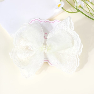 Close-up of white lace bow hair clip with double-row pearls on pink display card