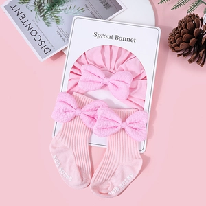 Pink cotton baby hat and socks set featuring textured bow detail and non-slip grips