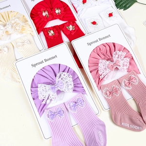 Detail of baby cotton bonnet with lace bow and matching knitted socks in various colors