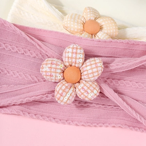 Détail du bandeau tricoté pour bébé avec fleur à paillettes et maille torsadée