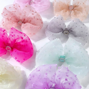 Close-up of colorful polka dot mesh bow hair clips with central rhinestone decoration