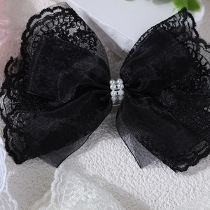 Close-up of black lace bow hair clip with six elegant pearl embellishments