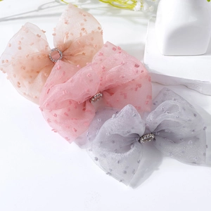 Detailed view of layered mesh bow hair clips with polka dots and rhinestone centers