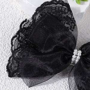 Detailed close-up of a black lace bow hair clip with decorative white pearls for girls
