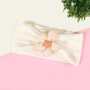 Vue détaillée d'un bandeau pour bébé en maille côtelée crème avec une fleur à carreaux orange