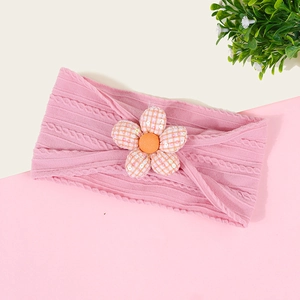 Gros plan du bandeau tricoté rose pour bébé avec fleur à carreaux orange pailletée