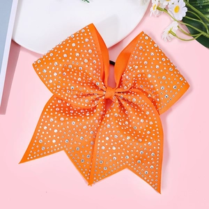 Detail of large orange bow hair tie with sparkling rhinestones on textured grosgrain ribbon