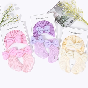 Cotton baby bonnet and socks set with textured bows in pink, lilac, and beige colors