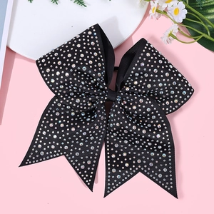 Detailed macro shot of a black bow hair clip featuring colorful sparkling rhinestones