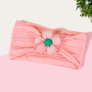 Détail du bandeau tricoté rose pour bébé avec fleur à carreaux et centre vert vif