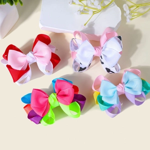 Detailed view of layered grosgrain ribbon bow hair clips in vibrant multi-color patterns