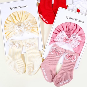 Detailed view of baby turban and socks set with lace bow ornaments in retail packaging