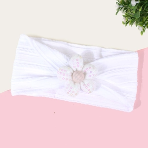 Gros plan du bandeau bébé blanc côtelé avec fleur à paillettes roses et centre rayé