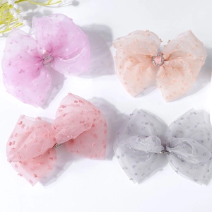 Close-up of four colorful bow hair clips with polka dots and rhinestones