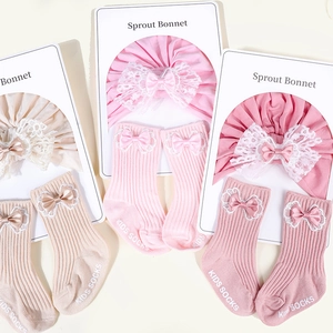 Detail of cotton baby bonnet and matching socks set with lace bows and ribbed texture