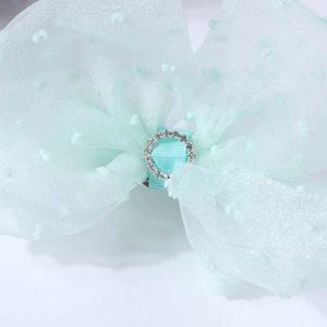 Detailed macro view of mint green mesh hair bow with 3D dots and sparkling rhinestone center