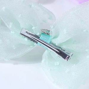 Detail view of mint green bow hair clip showing silver metal alligator clip and rhinestones