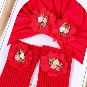 Detailed view of red cotton baby hat and ribbed leg warmers with handmade floral accents