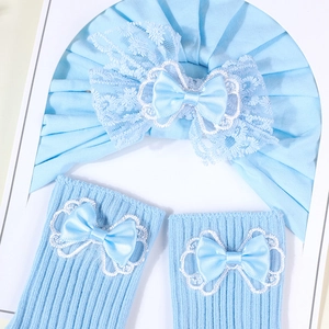 Detail of light blue baby turban and socks with delicate white lace and satin bows